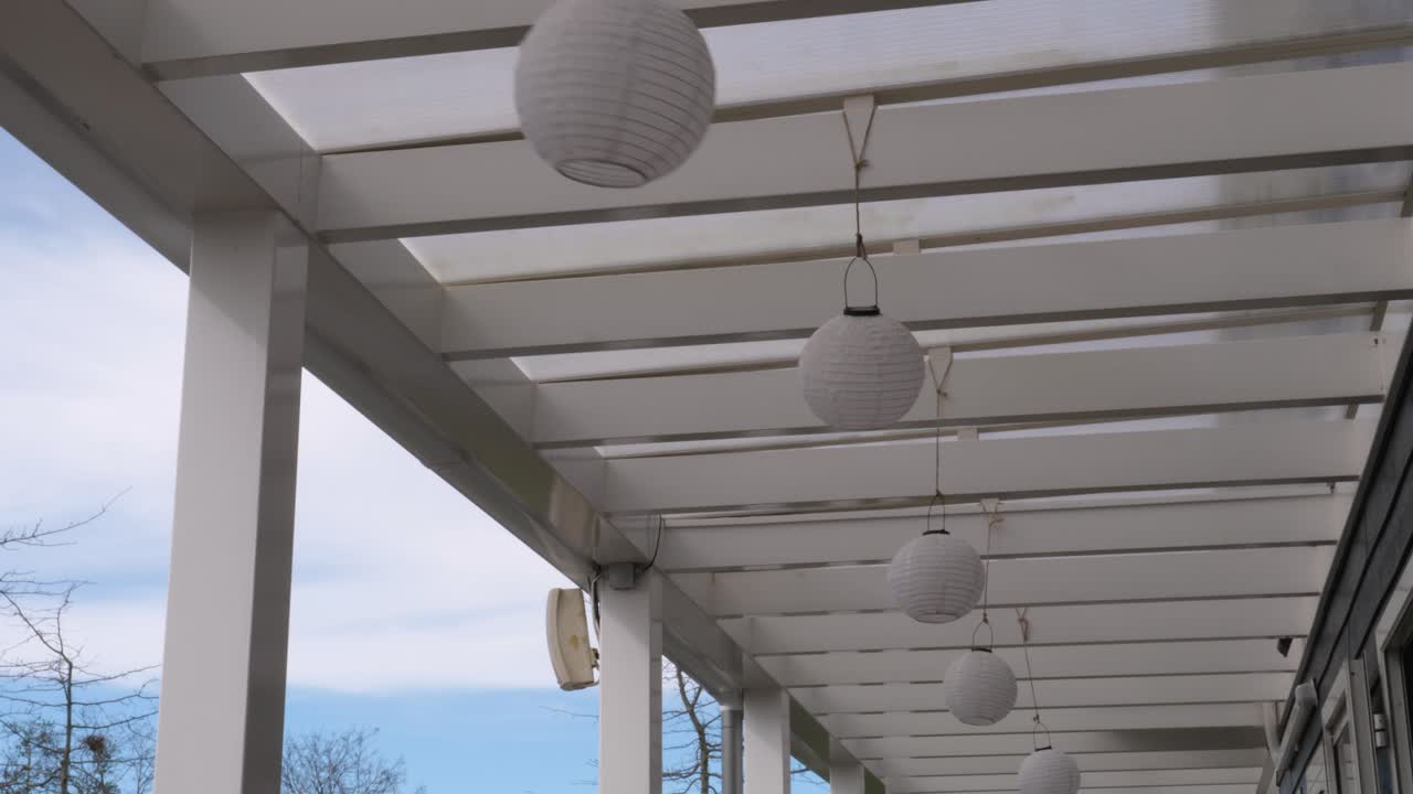 Round paper lanterns sway in the breeze on the open veranda.