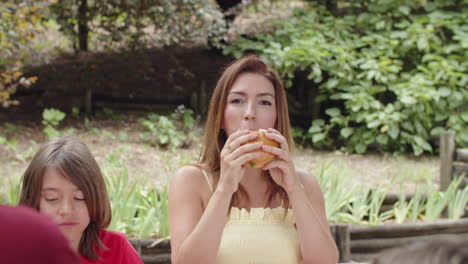 plano medio de madre e hijo comiendo durante un picnic en el bosque