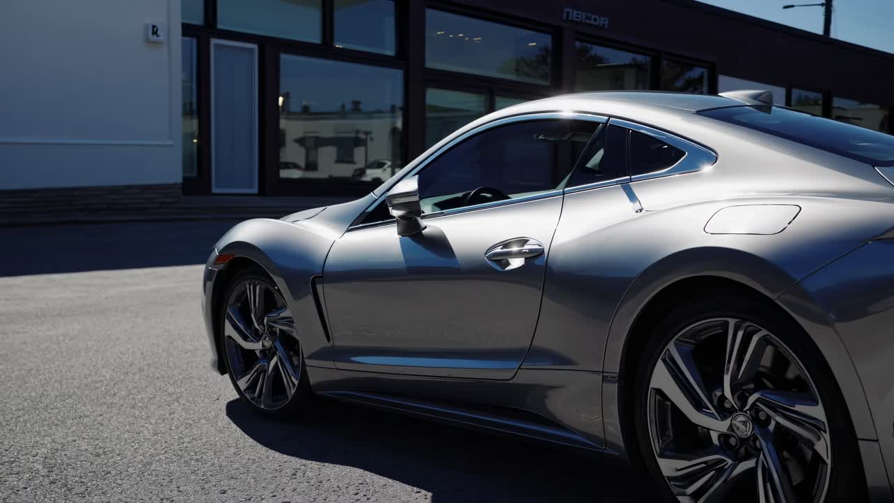Sleek silver sports car captured in a low-angle shot, highlighting its curves and design