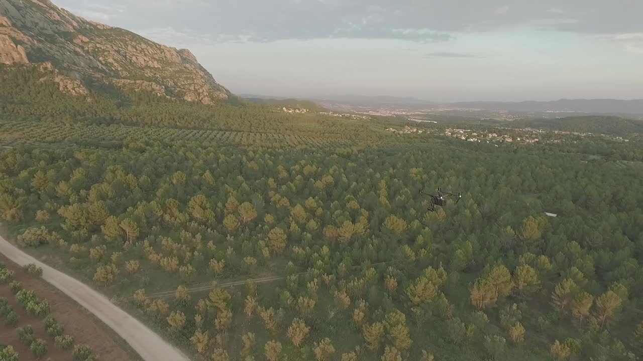 dando vueltas alrededor de un dron profesional en el paisaje montañoso y forestal, aéreo