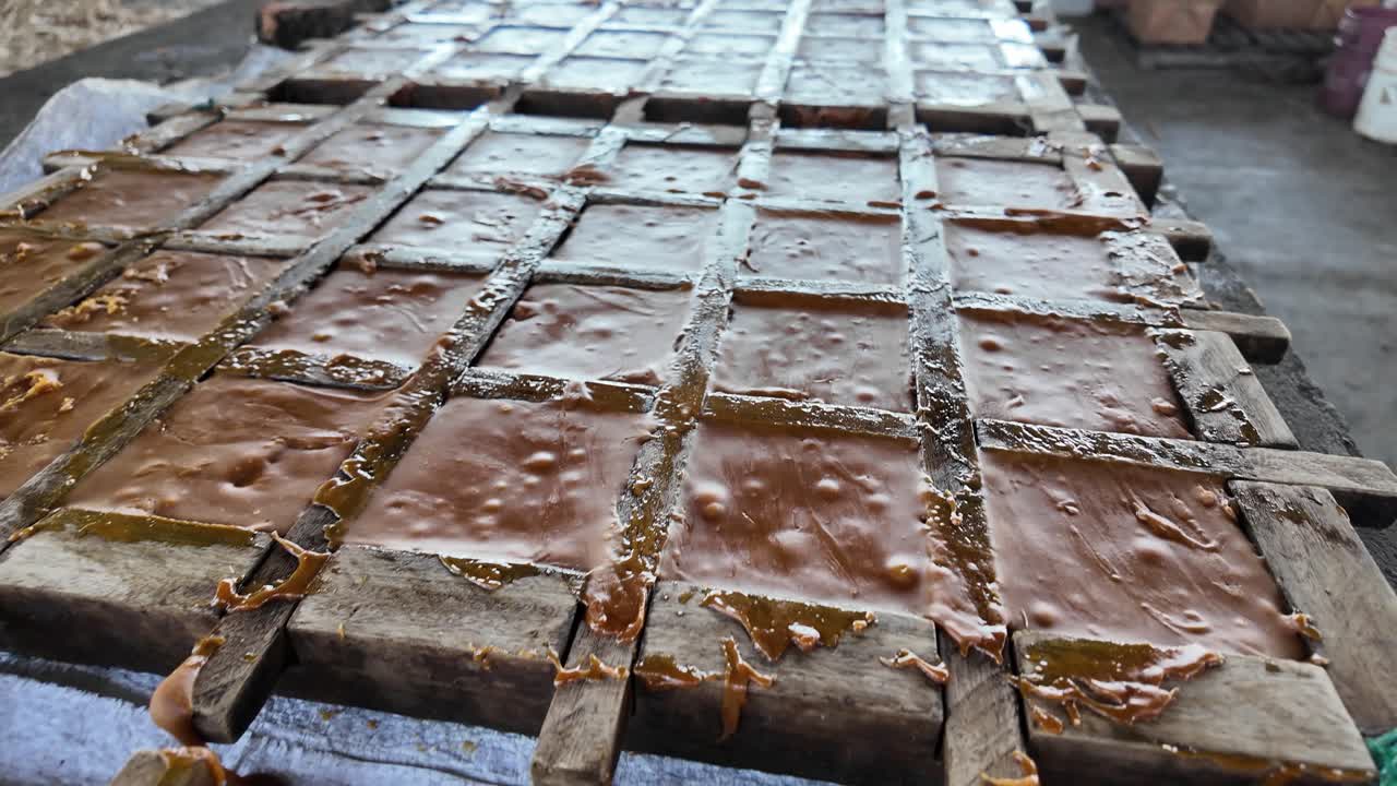 Caramelized sugar cane juice poured into wooden molds for brown sugar blocks