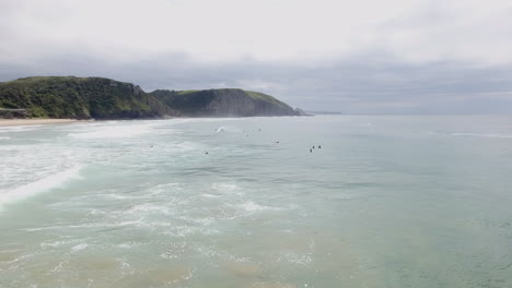 Cinematic-flying-of-surfers-surfing-along-coast-of-East-London-South-Africa-aerial