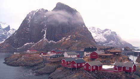 fog and clouds behind a red fishing village in the arctic lofoten islands norway