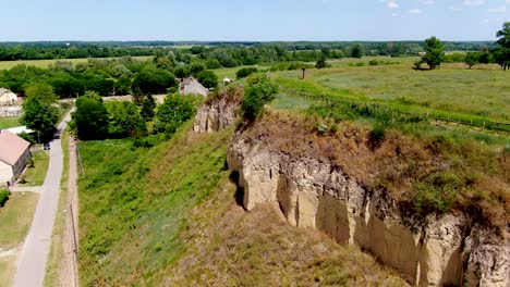 Vista-Desde-El-Acantilado-De-Un-Castillo-De-Tierra-En-Ersekhalma,-Hungría-En-Un-Día-Soleado-Con-Exuberantes-Campos-Verdes-Y-Casas-De-Campo