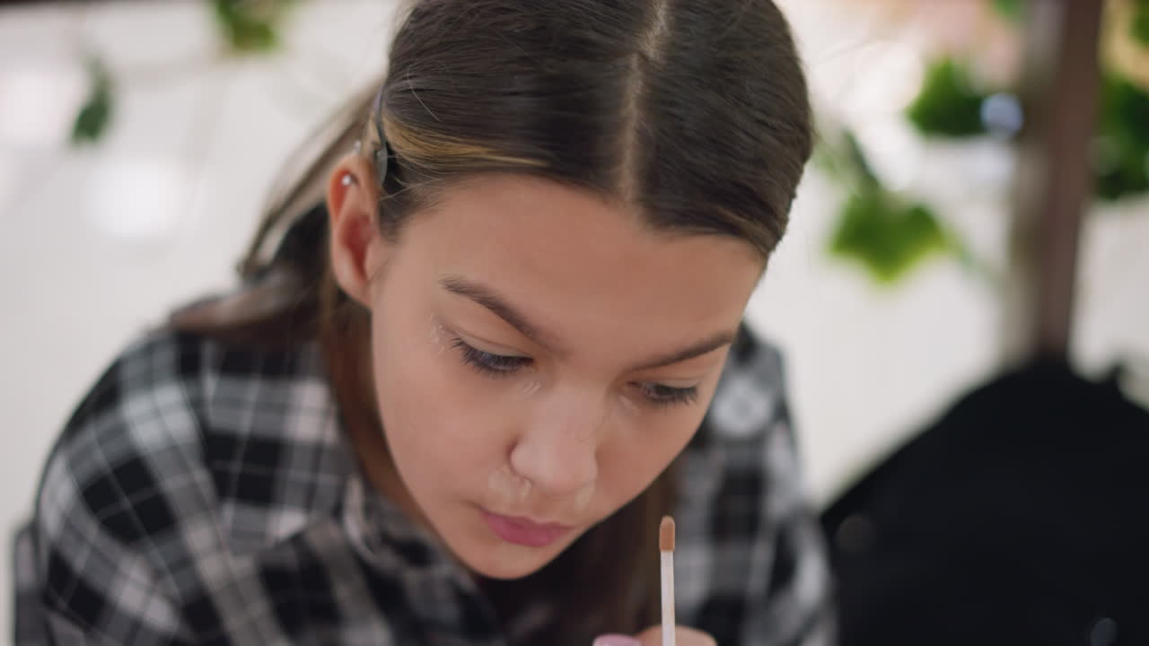 Young girl carefully tapping powder on face to achieve smooth, flawless makeup application, focused beauty routine in well-lit, enhancing skin tone and blending foundation for an even complexion