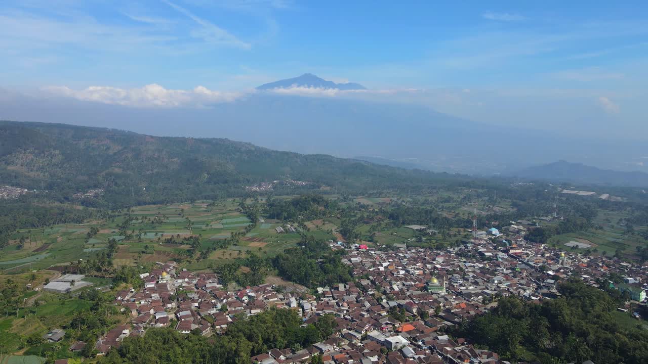 Breathtaking 4K aerial footage of a tranquil rural landscape with lush fields and a towering mountain backdrop. Ideal for nature, travel, and documentary content