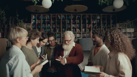 autor anciano firmando libros para un grupo de fans durante un evento en la biblioteca