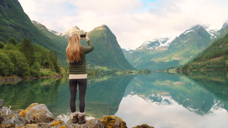 woman taking photo of norwegian fjord landscape