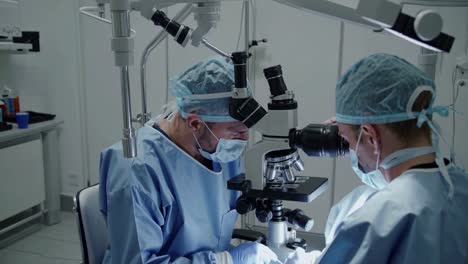 surgeons operating under microscope