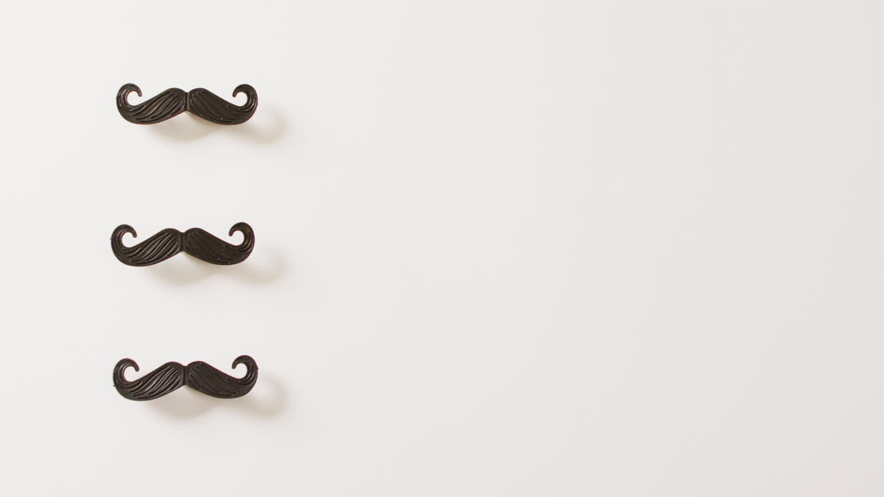 Video of three black false moustaches on white background with copy space