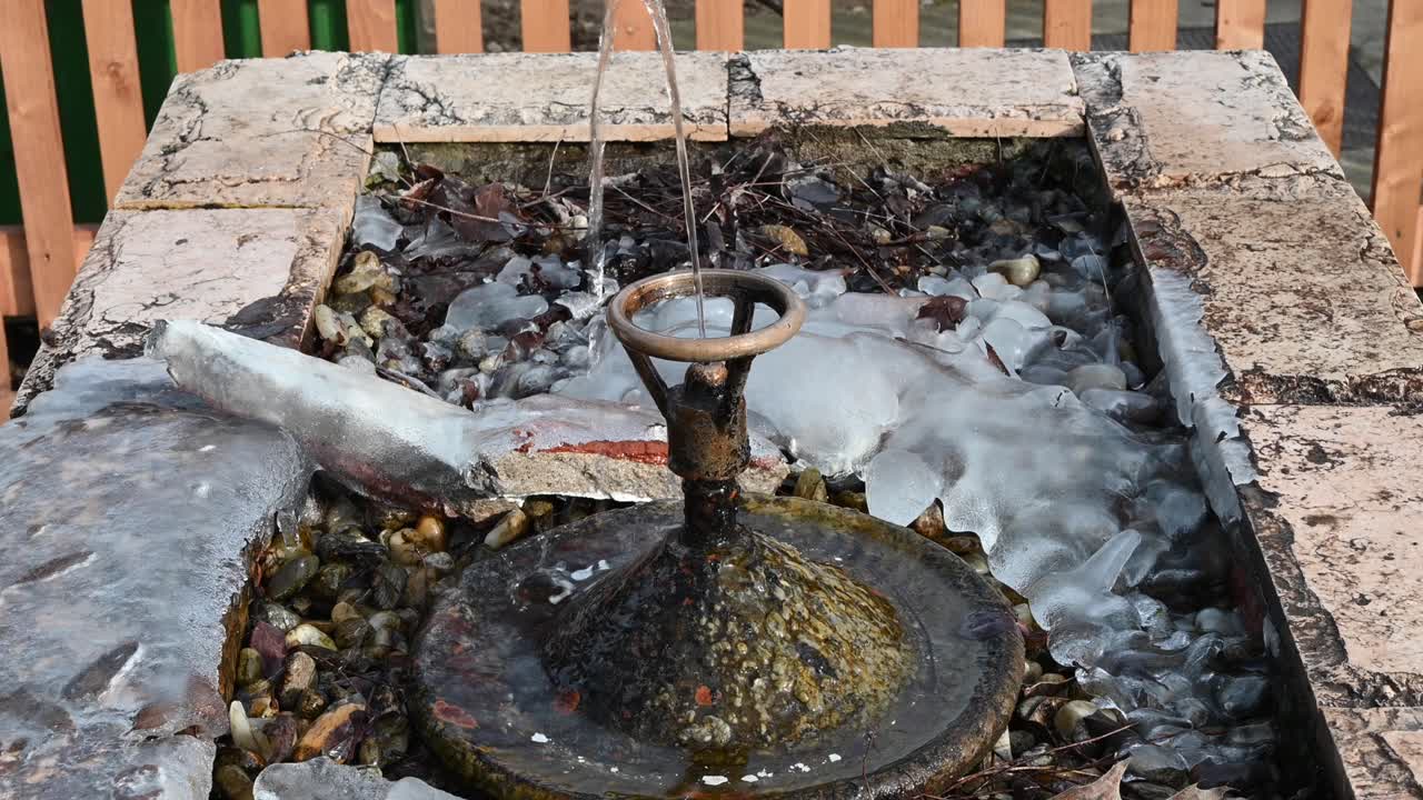 Close up of water spraying out of a fountain with ice around it