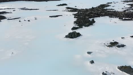 natural milky pools surrounded by black volcanic rock in iceland, aerial