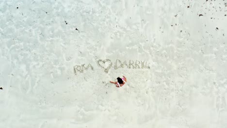 ascending view of woman writing love note on white sand beach with feet 4k