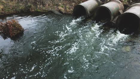 flying over concrete sewers. streams of water flow through concrete pipes. polluted body of water in the park