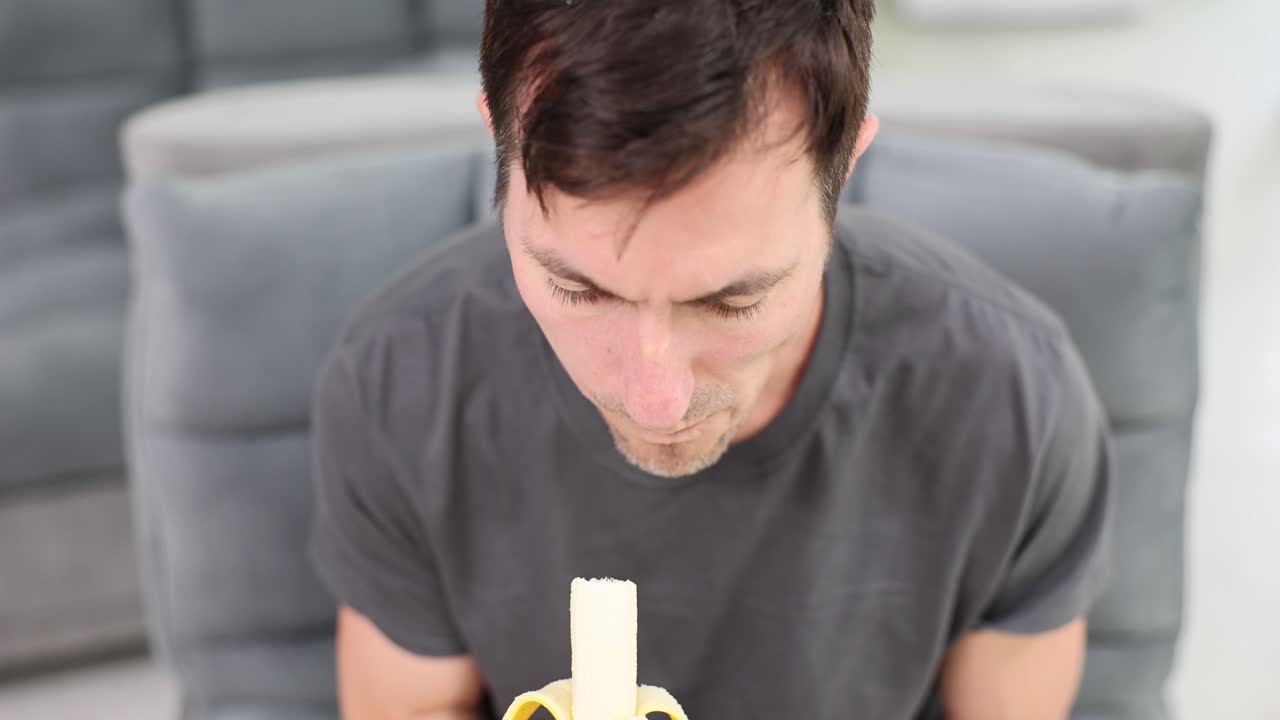 Man eating a banana while sitting on a couch