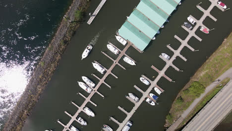 aerial top down orbital view of boats docked at marina docks next to road at port alberni region, vancouver island, british columbia canada