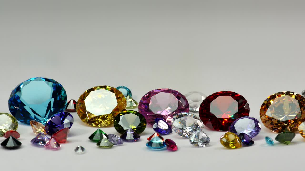 Diamanti colorati di varie dimensioni che brillano su uno sfondo bianco