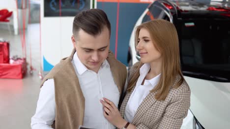 male dealer passing car documents to happy couple. auto business, car sale, technology and people concept