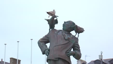 a medium daytime shot of the alfred hitchcock statue in dinard, france. captured in winter under a grey sky, the scene reflects the filmmaker’s iconic presence and the town’s cinematic charm.