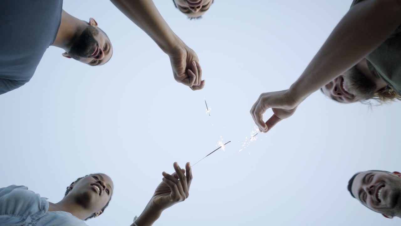 Bottom view of happy people dancing with bengal lights
