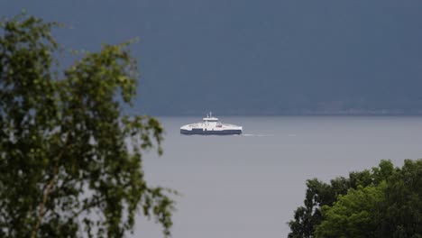 ferry boat sailing on calm fjord with mountains in background