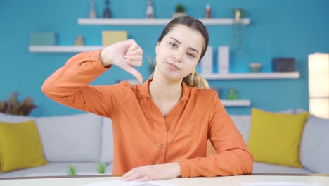 uneasy and unhappy young woman working in home office giving dislike sign.