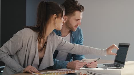 pareja caucásica sentada en la cocina y eligiendo colores para un nuevo apartamento