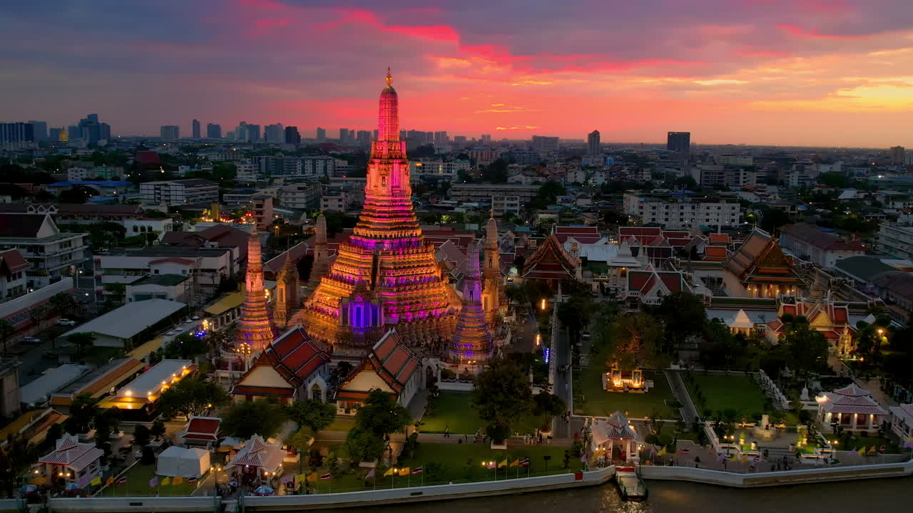 Orbit around Illuminated Wat Arun Temple and sunset over Bangkok