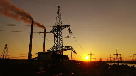 industrial factory and electricity pylons at sunset. silhouettes of high voltage power lines against the setting sun. industrial minimalist landscape.