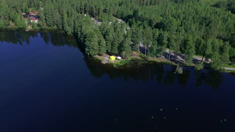 Reverse-tilting-drone-footage-over-a-small-lake-showing-the-energy-station-of-a-12-hour-ultra-marathon