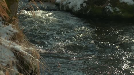 Primer-Plano-De-La-Corriente-Del-Río-De-Montaña-Con-Nieve-En-Cámara-Lenta