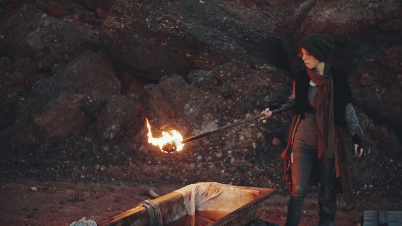 mujer poniendo una antorcha en la bañera con agua en un mundo post-apocalíptico