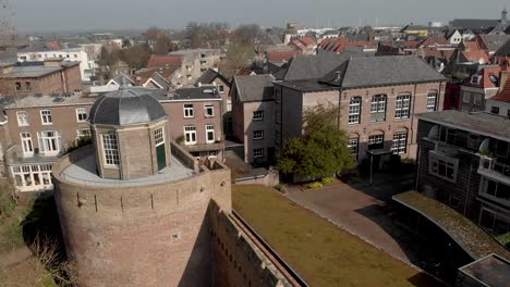 paneo lateral alrededor de la parte superior de la histórica torre de la fortaleza de bourgonje y la muralla de la ciudad en zutphen, los países bajos, con techo de vegetación de hierba en el otro lado y ramas de árboles que entran en primer plano