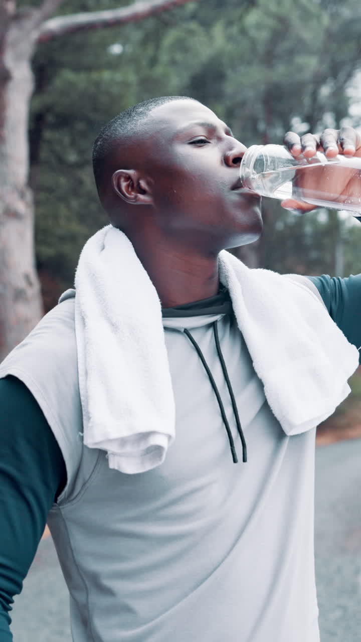 Jeune homme noir buvant de l'eau après un entraînement en plein air