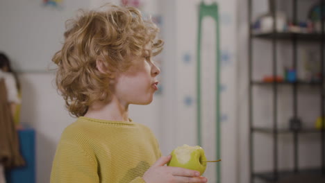 little boy eating an apple in classroom in a montessori school 1