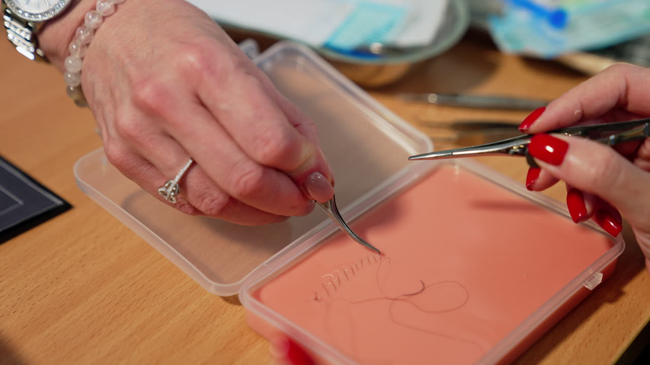 Student performed sewing on the skin model. Professor is checking and commenting the work done. Close up.