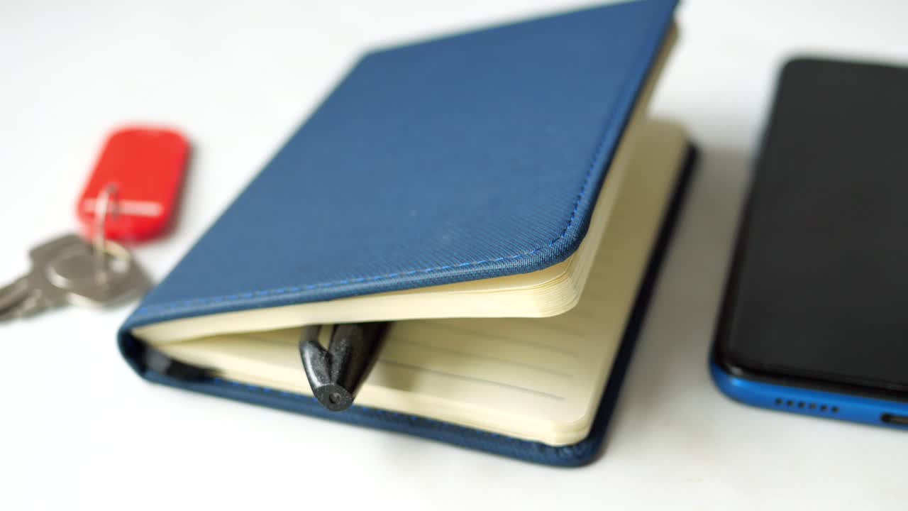 Notebook, Smartphone, and Keys on a White Surface