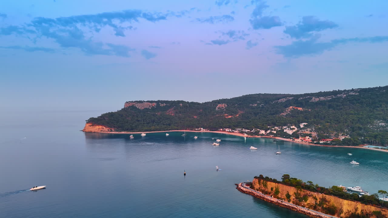 Modern white yachts on the calm waterscape at sunset. Aerial perspective on the rocky shoe of Kemer, Turkey