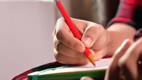 persona escribiendo con un lápiz rojo en un bloc de notas