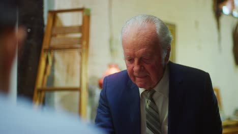 older man in suit drinks tea