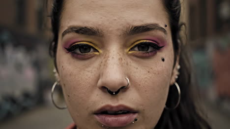 close-up portrait of a person with bold eye makeup and facial piercings