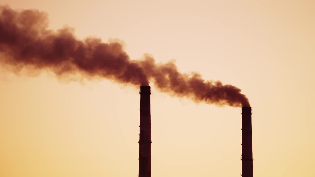 Dirty emissions are going into the air from pipes. Chemical smoke pollute the atmosphere of the evening sky. Close-up.
