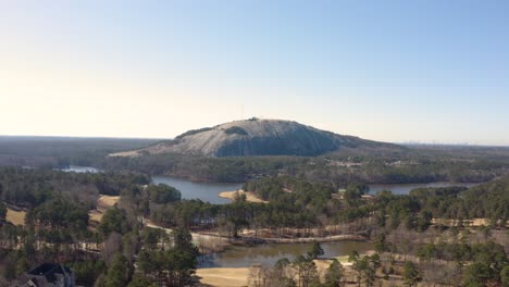 Aerial-drone-shot-slowly-flying-towards-the-confederate-memorial-on-the-side-of-Stone-Mountain-near-Atlanta,-Georgia-with-houses-and-a-golf-course-below