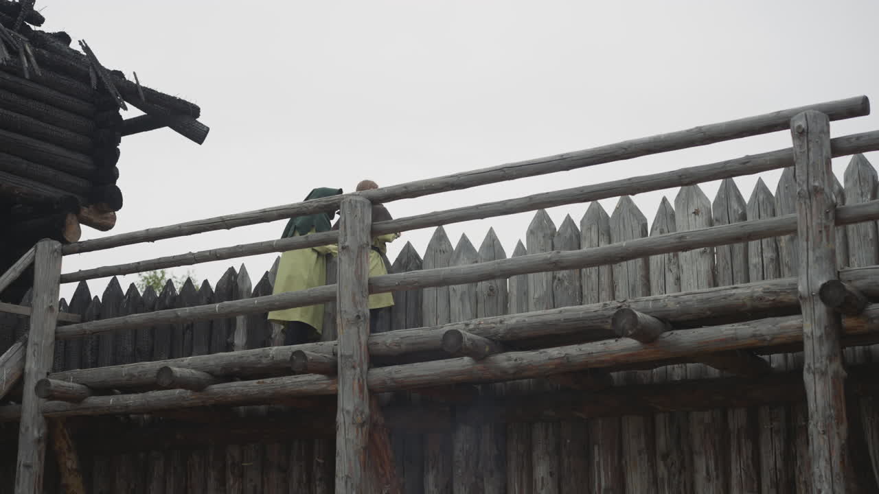 una pareja de personas de pie de guardia en el borde del asentamiento medieval