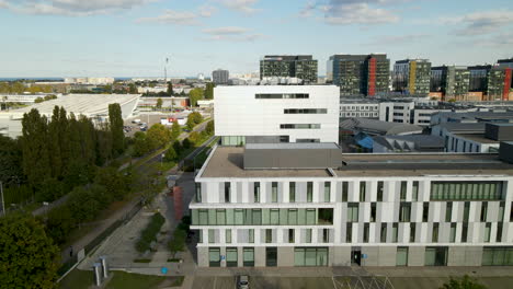 aerial drone orbit around sunny modern university city building in poland