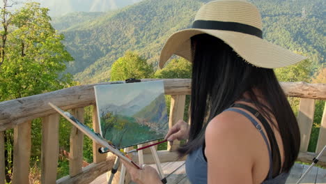 woman painting a mountain landscape outdoors