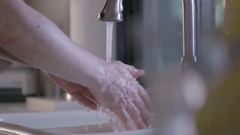 a caucasian male is cleaning and rinsing his hands in a home kitchen