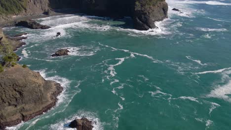 Blaugrüne-Wasserwellen,-Die-In-Der-Nähe-Von-Felsen-In-Brookings,-Oregon,-Zusammenbrechen.-4K-Drohnenaufnahmen