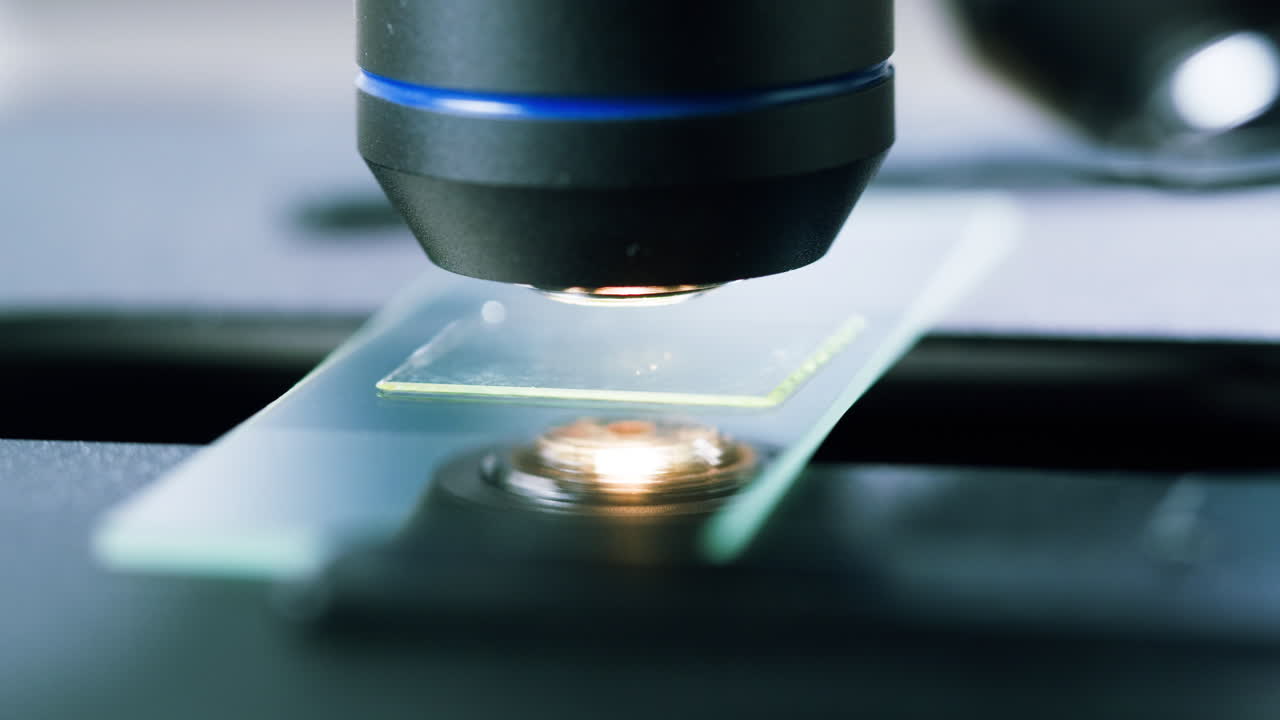 Scientific Microscope Focusing on a Glass Slide in a Laboratory