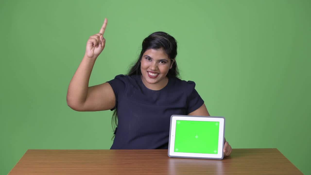 joven sobrepeso hermosa mujer de negocios india contra fondo verde